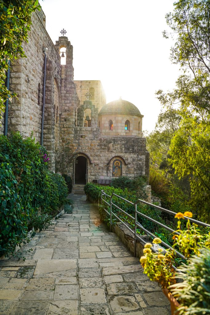 A peaceful walkway leading to a historic monastery bathed in sunlight.