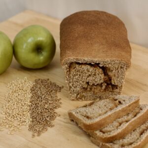 Photo of whole grain Abbot's apple bread, including organic green granny apples, organic soft white wheat berries, organic hard red heirloom wheat berries, and sliced loaf of Abbot's apple bread, made from organic ingredients.