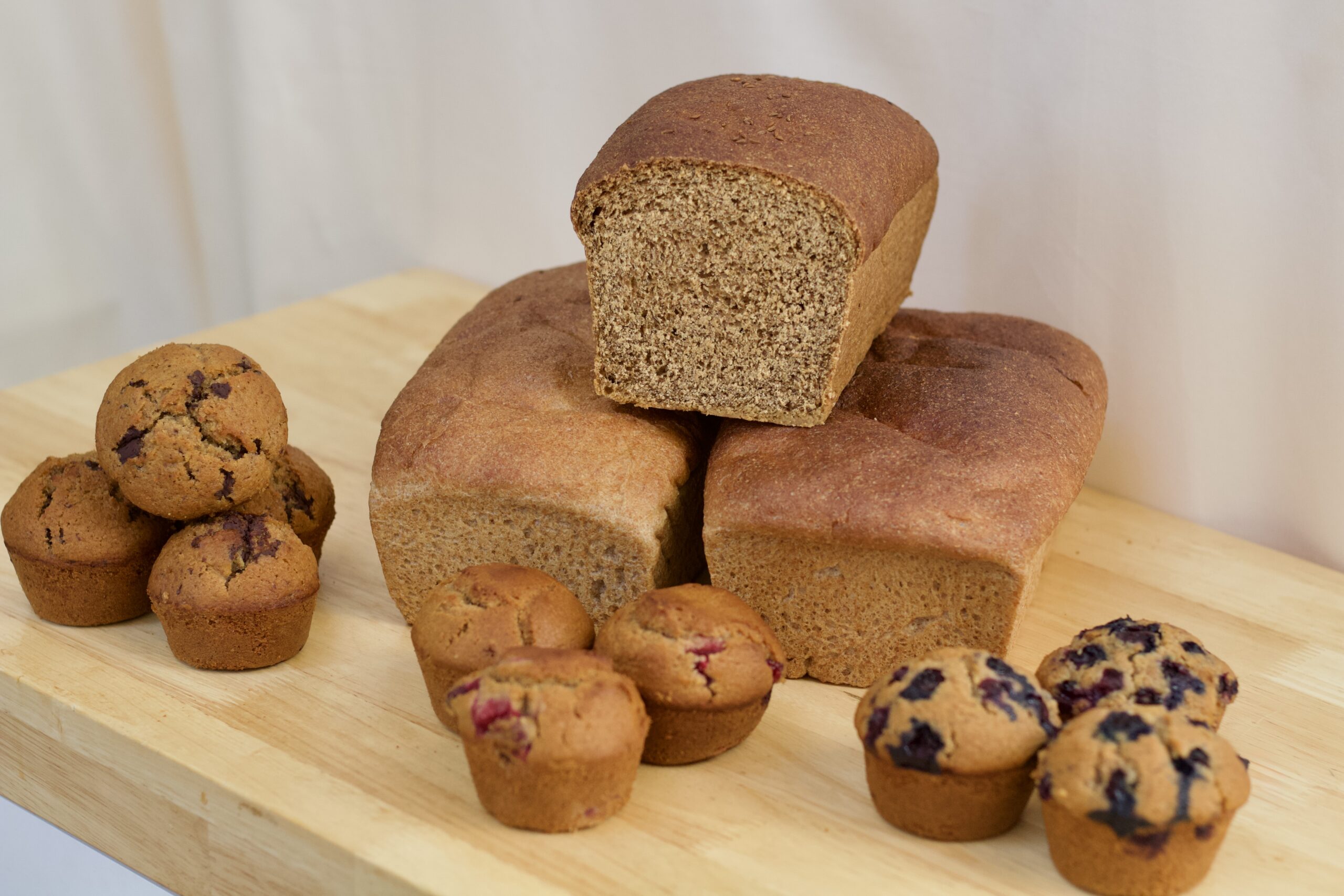 Stacked organic freshly milled whole grain bread and freshly milled organic whole grain muffins.